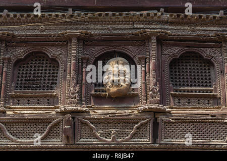 Das Fenster Detail und handgefertigte Maske hängen an der Außenseite des Gebäudes in Durbar Square in Kathmandu, Nepal Stockfoto