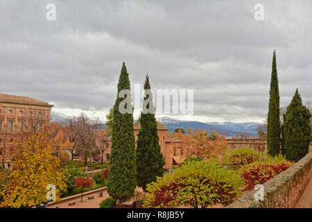 Terrasse mit Zypressen und die Berge der Sierra Nevada im Hintergrund an einem bewölkten Tag im Alhambra, Granada, Spanien Stockfoto