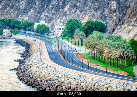 Gut gepflegt Küstenstraße entlang mit Datum Palm die Felder und die Berge. Von Muscat, Oman. Stockfoto