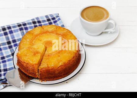 Hausgemachte Ananas Nach oben Torte mit einem Stück abschneiden und Tasse Kaffee auf weiße Holztisch Stockfoto