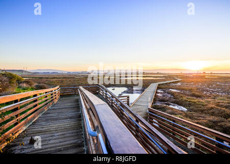 Holzsteg durch die Gezeiten Sümpfe von Alviso, Don Edwards San Francisco Bay National Wildlife Refuge, San Jose, Kalifornien; Sonnenuntergang Stockfoto