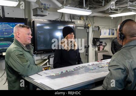 First Lady der USA Melania Trump, durch die US-Marine Kapitän Chris Hill beigetreten, Links, hört eine Erklärung über Maßnahmen der Flugzeugträger USS George H.W. Bush bei einem Besuch der Brücke am 12. Dezember 2018 in Hampton, Virginia. Die erste Dame bezahlt ein Weihnachten Besuch des Schiffes und der Service Mitglieder immer nur die erste Dame zu fliegen und landen auf einem Flugzeugträger an Bord eines V-22 Osprey Aircraft. Stockfoto