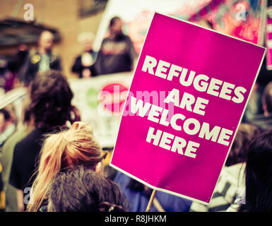 Viel befahrenen Straße Protestmarsch mit einem Schild, auf dem die Flüchtlinge willkommen sind Heren Stockfoto