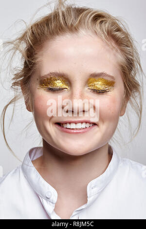 Lächelnd weibliche Gesicht mit geschlossenen Augen. Frau mit ungewöhnlichen Funkeln glitzernde vogue Gesicht Beauty Makeup. Mädchen mit perfekte Haut und gelbe rauchigen Augen Auge sha Stockfoto