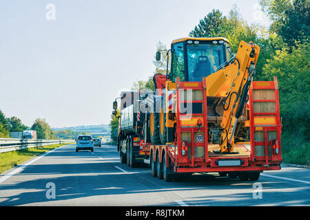 Lkw-Anhänger, Transporter mit gewerblichen Güterkraftverkehrsunternehmer landwirtschaftlichen Traktor auf der Straße, in Slowenien. Stockfoto