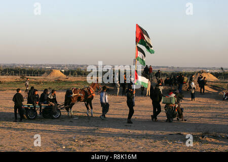 Gaza, Palästina. 14. Dezember 2018 Palästinenser tragen Plakate und eine palästinensische Flagge, wie Sie ein Protest innerhalb der 'Große März erneut auf die Bühne sammeln Stockfoto