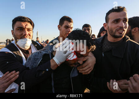 Gaza, Palästina. 14. Dezember 2018 einen verletzten Mann, während der israelischen Streitkräfte in palästinensische Demonstranten einmischen, so wie Sie es einem Protest in th Stufe Stockfoto