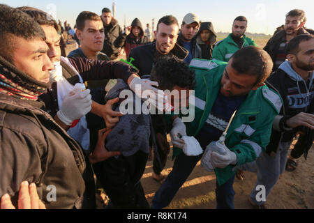 Gaza, Palästina. 14. Dezember 2018 einen verletzten Mann, während der israelischen Streitkräfte in palästinensische Demonstranten einmischen, so wie Sie es einem Protest in th Stufe Stockfoto