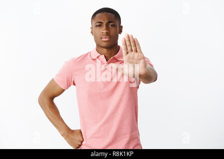 Kein Übertreten. Ernst - auf der Suche verantwortlich african american Guy ziehen Hand in Richtung Kamera im Anschlag oder Verbot Geste Haltearm auf Taille, ernste und konzentrierte sich dabei auf Eindringling Stockfoto