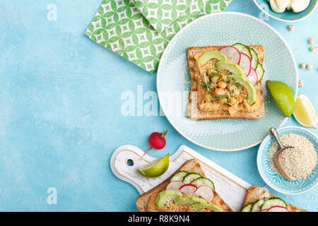 Toast mit Kichererbsen Hummus, Avocado, frische Radieschen, Gurken, Sesam und Leinsamen Sprossen. Diät Frühstück. Leckere und gesunde pflanzliche Veg Stockfoto