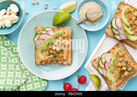 Toast mit Kichererbsen Hummus, Avocado, frische Radieschen, Gurken, Sesam und Leinsamen Sprossen. Diät Frühstück. Leckere und gesunde pflanzliche Veg Stockfoto