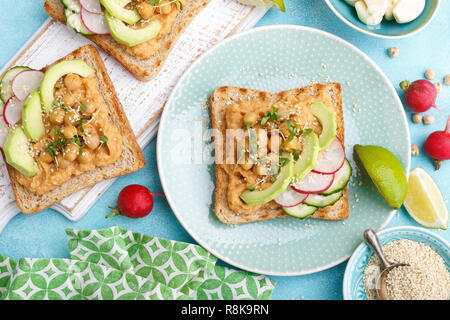 Toast mit Kichererbsen Hummus, Avocado, frische Radieschen, Gurken, Sesam und Leinsamen Sprossen. Diät Frühstück. Leckere und gesunde pflanzliche Veg Stockfoto