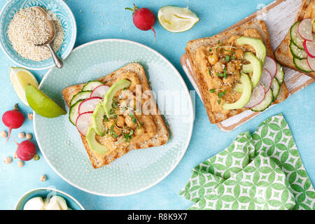 Toast mit Kichererbsen Hummus, Avocado, frische Radieschen, Gurken, Sesam und Leinsamen Sprossen. Diät Frühstück. Leckere und gesunde pflanzliche Veg Stockfoto