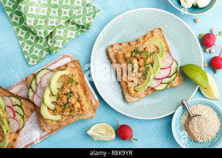 Toast mit Kichererbsen Hummus, Avocado, frische Radieschen, Gurken, Sesam und Leinsamen Sprossen. Diät Frühstück. Leckere und gesunde pflanzliche Veg Stockfoto