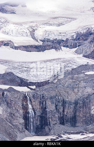 Hohe Wasserfall über raue Landschaft aus Stein und Gletscher Stockfoto