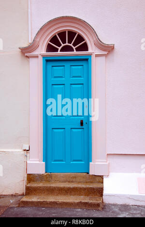 Helle blaue Tür in hellem rosa Wand, Lyme Regis, Dorset, England Stockfoto