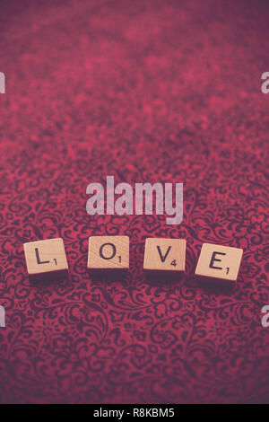 WOODBRIDGE, NEW JERSEY, November 9, 2018: Scrabble Tiles, buchstabieren Sie das Wort Liebe auf einem hübschen Stoff Hintergrund Stockfoto