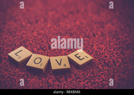WOODBRIDGE, NEW JERSEY, November 9, 2018: Scrabble Tiles, buchstabieren Sie das Wort Liebe auf einem hübschen Stoff Hintergrund Stockfoto