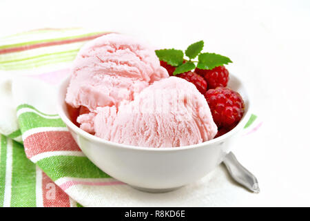 Eis crimson mit Himbeeren, Beeren und Minze in weiße Schüssel, einen Löffel auf dem Handtuch auf dem Hintergrund des Lichts Holzbrett Stockfoto