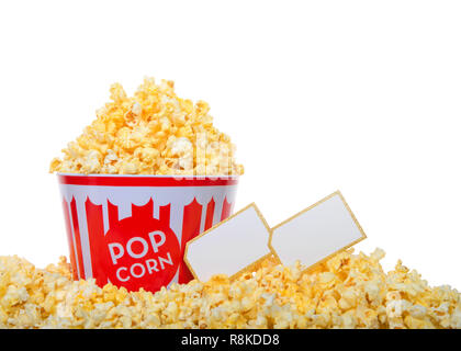 Eimer mit Pop Corn gehäuft Hoch mit Popcorn und von der gleichen, auf weißem Hintergrund umgeben. Zwei leere Kinokarten neben Schaufel. Stockfoto