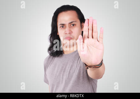 Foto Portrait von einem netten gutaussehenden jungen asiatischen Mann mit langen Haaren, stop Geste mit Verärgerten Gesicht, auf Palm mit blur konzentrieren Stockfoto