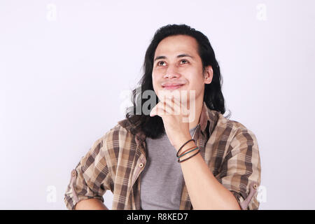 Foto Bild Portrait einer netten jungen asiatischen männliche Kursteilnehmer mit langen Haaren, lächelnd, bis suchen, sein Kinn berühren und Denken Stockfoto