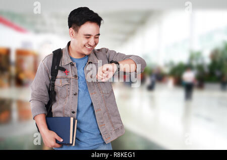 Konzept, foto Bild Porträt eines erfolgreichen cute jungen asiatischen männliche Kursteilnehmer lächelnd und mit Blick auf seine Armbanduhr, halb Körper, Nahaufnahme, Porträt Stockfoto