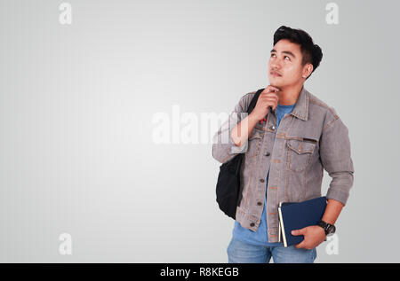 Foto Bild Portrait einer netten jungen asiatischen männlicher Student und habe nach oben geschaut und denken, während Sie einige Bücher Stockfoto