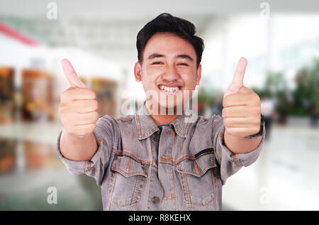 Foto Portrait von eine nette junge asiatischer Mann lächelnd und mit zwei Daumen hoch Stockfoto