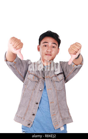 Foto Portrait von eine nette junge asiatischer Mann tun spöttische Geste und zeigt zwei Daumen unten isoliert auf weißem Stockfoto