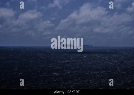 Die Ghost Ship. Ein Schiff am Horizont hinter der kleinen Insel Fifla außerhalb der Küste von Malta. Stockfoto