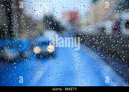 Regen auf Glas. Regen vor dem Fenster auf dem Hintergrund der Lichter der Stadt. Tropfen Wasser fällt auf Glas bei Regen. Wassertropfen über Fenster Glas d Stockfoto