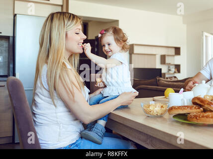 Ein Kind füttert ihr Mutter im Zimmer. Stockfoto