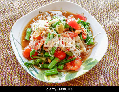 Das Essen im Thai Stil Papaya Salat mix Reis Nudeln/Green Papaya Salat Nudeln auf dem Teller heiß und würzig mit pflanzlichen Yard lange Bohnen und Tomaten auf Platte Stockfoto