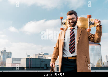 Fröhliche Geschäftsmann holding Penny board und lächelnd in Gläser Stockfoto
