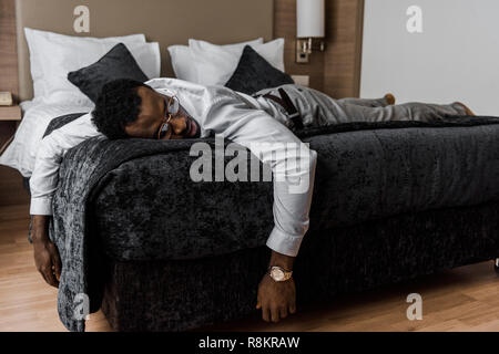 Erschöpft african american man schlafen auf Bett im Hotelzimmer Stockfoto