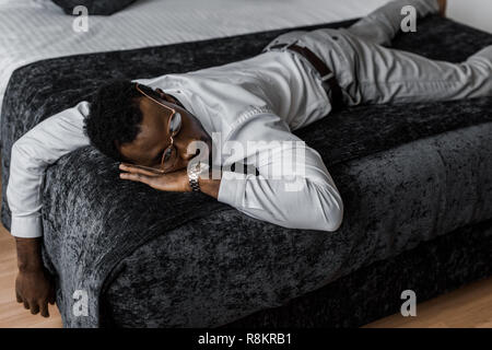 Erschöpft afrikanische amerikanische Mann in formale Abnutzung Schlaf im Bett im Hotelzimmer Stockfoto