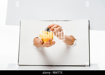 Schoß der Frau setzen Bitcoin in Gelb piggy Bank durch die Löcher 7/8 auf Weiß Stockfoto