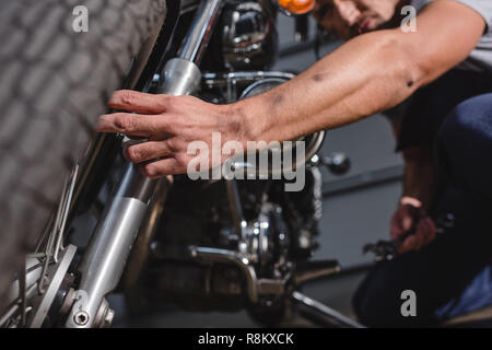 Nahaufnahme der Mechaniker zur Festsetzung Motorrad Vorderrad in einer Garage. Stockfoto