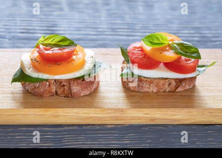 Zwei bruschetta Caprese auf Holzbrett auf grau Holztisch. Stockfoto