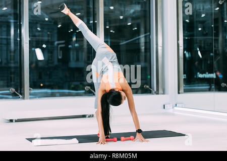 Schlanke Mädchen stretching Bein auf Fitness Matte zum Fitnessraum Stockfoto