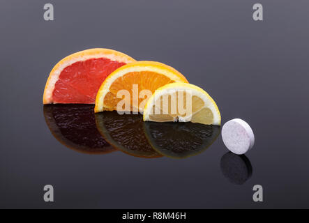 Grapefruit-, Orangen- und Zitronenscheiben und ein vitamin Tablette. Natürliches Vitamin C vs. Synthetische Vitamine. Stockfoto