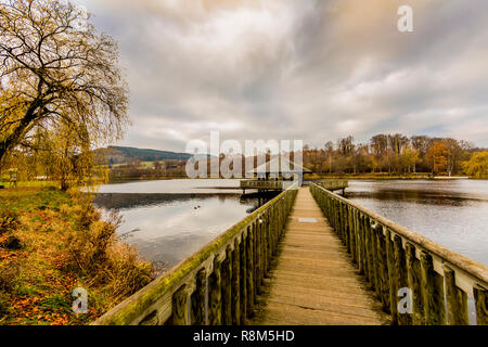 Bild eines hölzernen Fußweg führt zu einem Pavillon in der Mitte des Doyards See in Vielsalm an einem bewölkten Herbst Tag in den Belgischen Ardennen Stockfoto