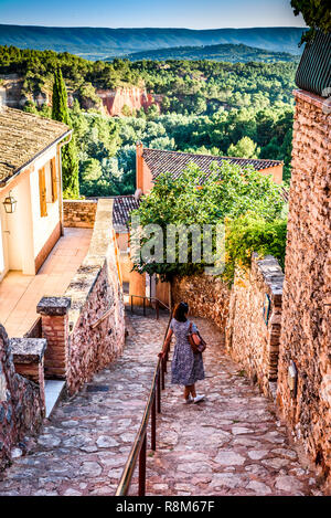 Ansicht in einer Gasse in Roussillon Frankreich mit einer Dame bewundern die schöne Ockerfarben und Landschaft der Provence in der Ferne. Stockfoto