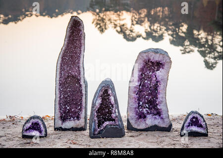 2 große und 3 kleine Amethyst Crystal Geoden in der Nähe der Wasser eines Sees bei Sonnenuntergang Stockfoto