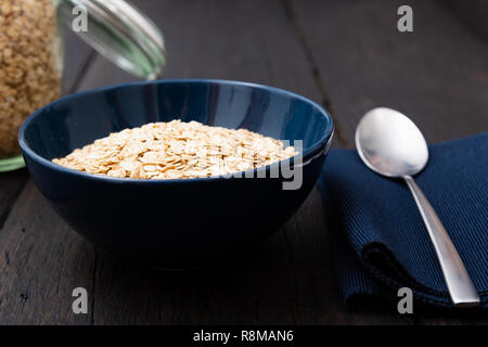 Haferflocken, gesundes Frühstück Müsli Haferflocken in der Schüssel auf dunklen Holztisch mit Textur Stockfoto