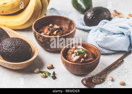 Avocado Mousse au Chocolat mit Pistazien in eine hölzerne Schüssel auf einem weißen Hintergrund. Stockfoto
