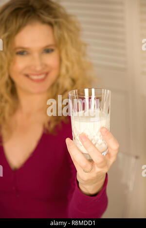 Junge blonde Frau mit einem Glas Milch Stockfoto