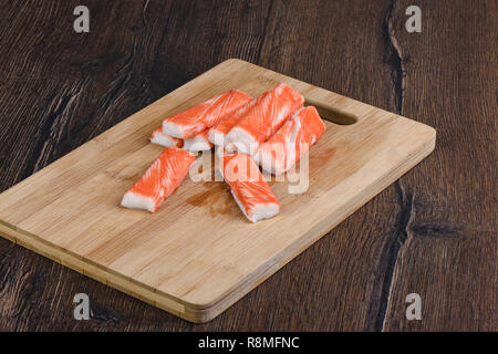 Im rustikalen Stil. Crab Sticks auf einem Schneidebrett auf hölzernen Hintergrund Stockfoto