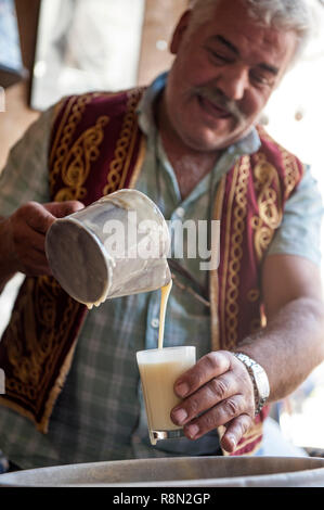 Huseyin Die Boza Hersteller von Ortahisar. Boza ist ein traditionelles Türkisches fermentiert malt Drink von bulger, Reis, Hefe und Kichererbsen mit Zimt gemacht. Kappadokien in der Türkei ist wie das Land der schönen Pferde im Herzen der anatolischen Türkei bekannt. Stockfoto